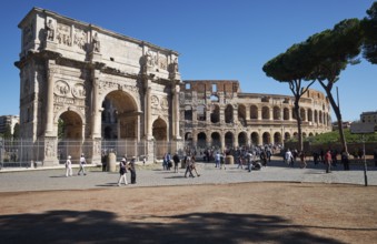 Arch of Constantine and Colosseum surrounded by tourists under blue sky, Rome, Lazio, Italy
