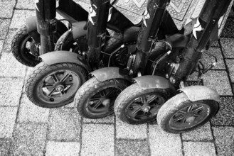 Black and white view of lined up, parked e-scooters on a paved surface, Singen am Hohentwiel,