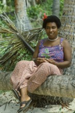 Woman (Katherina) sitting on a coconut trunk on the beach, Tavewa Island, Yasawa Islands, Fiji