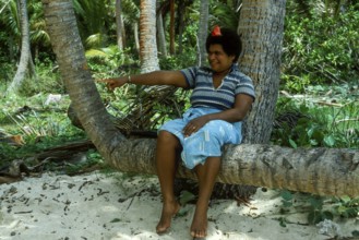Woman sitting on a coconut trunk, (there are no chairs on Tavewa) Tavewa Island, Yasawa Islands,