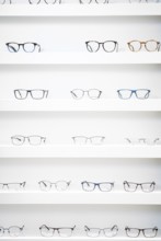 Several pairs of glasses neatly arranged on shelves in an optician's shop, optician, Pforzheim