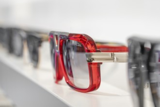 Different sunglasses with red accents on a shelf, optician, Pforzheim