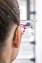 Woman wearing a hearing aid and glasses, close-up in an optical environment, optician, Pforzheim