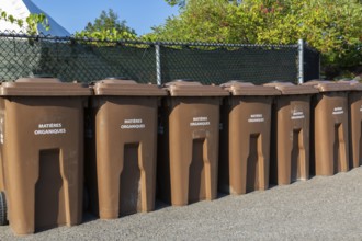 Row of brown plastic heavy duty portable composting bins for depositing organic materials and
