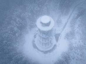 A snow-covered treetop trail soars high in foggy winter weather, Himmelsglück observation tower