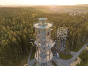 A high observation tower in the forest, surrounded by trails and illuminated by evening light,