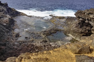 Rocky coastline with clear turquoise water pools and nearby waves, Yaiza Lanzarote