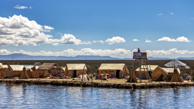 Reed huts and people on an island under a partly cloudy sky with a wide landscape, The floating
