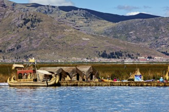 Reed boats and huts on a lake with mountains in the background, The floating reed islands of the