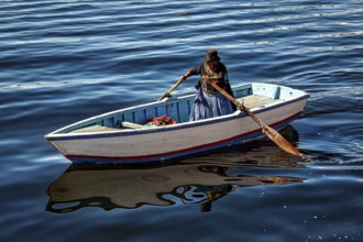 Woman rowing in a traditional boat on the calm waters of the lake, The floating reed islands of the