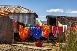 Colourful clothes hang on a line between traditional buildings under blue skies, The floating reed