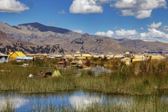 A rural area with huts, reeds and boats against a mountain backdrop and blue skies, The floating