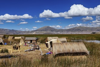 A village with reed huts on a lake under a cloudy blue sky, The floating reed islands of the Uros