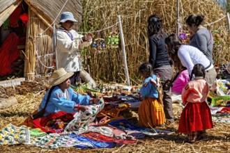 People and children sell and look at crafts in a village made of straw huts, the floating reed