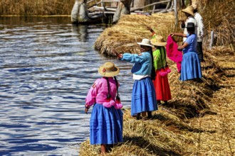 Women in colorful traditional clothing stand on the shore and look out at the water, the floating