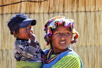 Woman wearing colorful hat carrying a child in her arms, both in traditional clothing, The floating