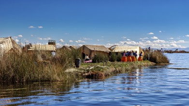 Reed huts on an island in the lake with people wearing colorful traditional clothing, The floating