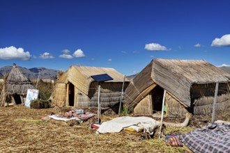 Traditional reed huts with solar panels on a lake surrounded by mountains, The floating reed