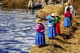 A group of woman in colorful, traditional clothing on the watery shore, The floating reed islands