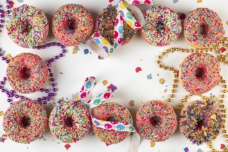 Donuts with sprinkles and confetti surrounded by streamers and strings of pearls on a bright