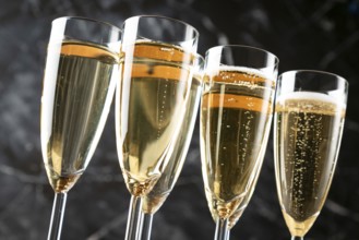 Filled champagne glasses with foaming contents against a dark background