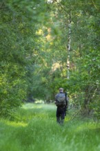 Hunter with backpack and gun goes to the residence, Ahlhorn, Lower Saxony, Germany