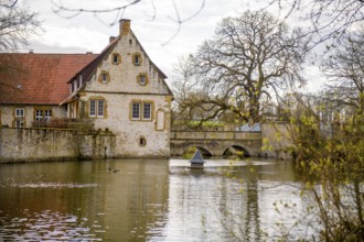 An old moated castle in Melle Haus Sondermühlen with bridge, surrounded by a large pond and trees