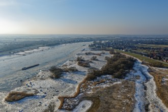 On a cold winter day, a barge sails downstream on the Elbe near Hamburg when there is slight ice.