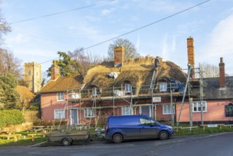 Thatcher at work replacing thatch ridge of thatched country pub building, Sorrel Horse, Shottisham,