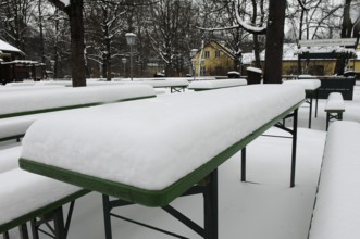 Winter in the English Garden, snow-covered beer garden tables and benches, Munich, Bavaria, Germany