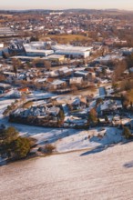 Wintery city view with snow-covered houses and trees in soft orange tones, Hallwangen, Freudenstadt