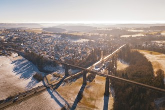 Snowy landscape with bridge and wide view of a village in warm light, Aach, Dornstetten,