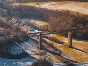 Bridge spanning a snowy valley next to a village under mild sunlight, Aach, Dornstetten,