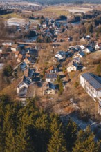 Aerial view of a snowy village surrounded by thick forests and hills, Aach, Dornstetten,