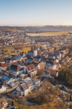 Aerial view of a town with church in the center, surrounded by buildings and winter landscape under