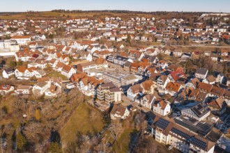 Aerial view of a city with many buildings and red roofs, in a wintry landscape in sunshine,