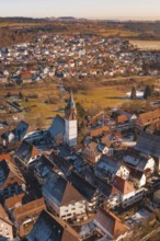 Aerial view focusing on church surrounded by city buildings in a wintry environment in sunlight,