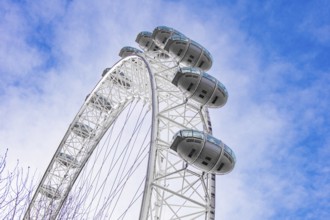 View of a Ferris wheel with white cabins against a blue sky, London Eye, London, United Kingdom