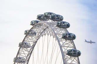 Ferris wheel with an airplane in the blue sky in the background, London Eye, London, United Kingdom