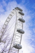 A large Ferris wheel juts into the blue sky surrounded by clouds, London Eye, London, United