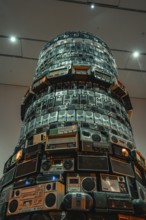 Tower-like installation of stacked radios in a brightly lit room, Tate Modern of Art, Lodon, United