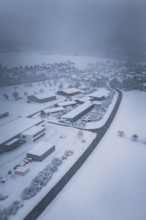 Winter aerial view of a snowy village surrounded by a winding road, Hörschweiler, Freudenstadt