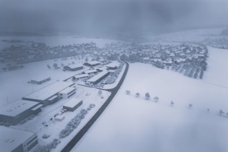 Wintery snowy village with buildings and roads under a thick blanket of fog, Hörschweiler,