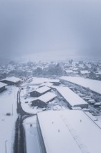 Snowy village landscape with buildings under a cloudy sky, Hörschweiler, Freudenstadt district,