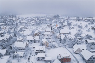 Village in winter with a church and snow-covered roofs in quiet surroundings, Schopfloch,