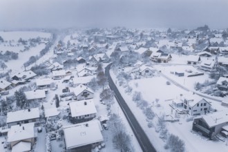 Aerial view of a snowy village with snow-covered buildings and cloudy sky, Schopfloch, Freudenstadt