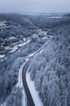 Snowy road through a forest, quiet winter landscape with lonely car, Altensteig, Calw district,