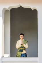 Young man in traditional clothing presenting himself to photographers, Wat Arun Buddhist temple,