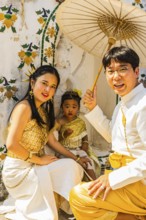 Young family with toddler and parasol in traditional clothing present themselves for the