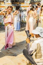 Young woman in traditional clothing presents herself to photographers, Wat Arun Buddhist temple,